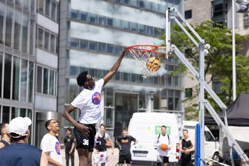 Ein großer Basketballspieler dunkt den Ball bei einem Streetball Tunier.