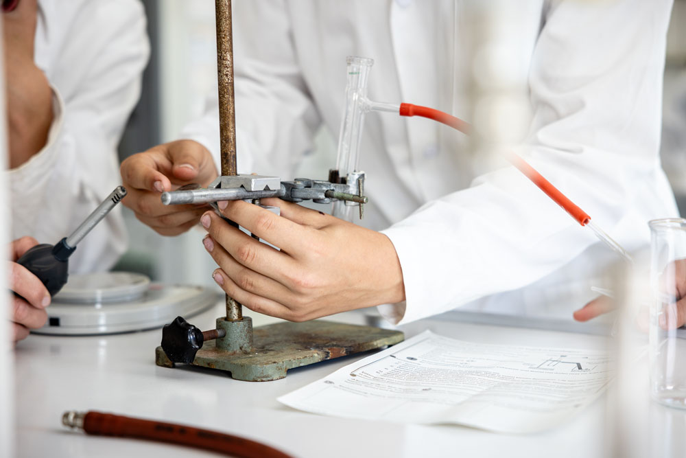 Schülerinnen in weißen Kitteln beim Chemieexperiment im Schullabor der Weiltalschule.